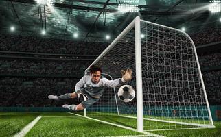 Soccer goalkeeper that makes a great save and avoids a goal during a match at the stadium photo