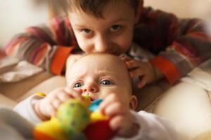 hermano con su pequeño hermana. el hermano suavemente Besos su hermana. foto