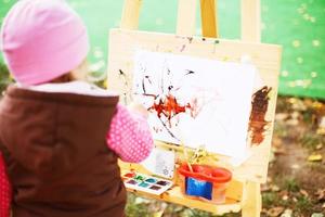 little girl draws  on the easel. the child paints photo