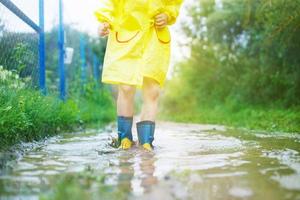 child's feet in a rubber boot in a puddle photo