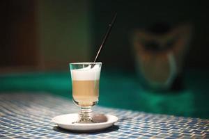 a cup of coffee in the pool and a girl in the background photo