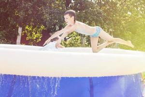 chico saltando dentro el nadando piscina en el jardín a verano foto