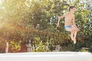 boy jumping into the swimming pool in the garden at summer photo