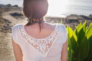 back view of a girl sitting on sandy beach alone on the sea background close photo