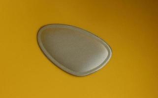 Simple light gray colored high heels or shoes insoles to insert inside foot wear. Object photo isolated on plain yellow background.
