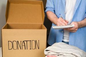 Closeup of a male volunteer writing donw number of donations. Chartiy concept photo