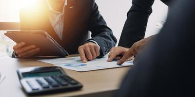 Financial analysts analyze business financial reports on a digital tablet planning investment project during a discussion at a meeting of corporate showing the results of their successful teamwork. photo