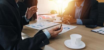 Financial analysts analyze business financial reports on a digital tablet planning investment project during a discussion at a meeting of corporate showing the results of their successful teamwork. photo