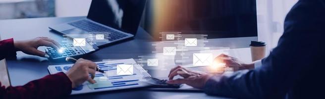Businessman hands using Laptop typing on keyboard and surfing the internet on office table with email icon, email marketing concept, send e-mail or news letter, online working internet network. photo