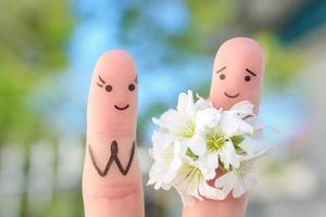 Fingers art of happy couple. Man is giving flowers to woman. photo
