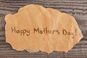 Concept of greeting Happy Mother's Day on old wooden background. photo