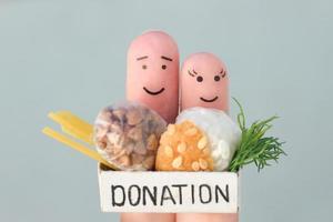 Fingers art of couple. Man  and woman holding donation box with food. photo