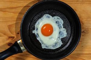 Cooking roasted eggs for breakfast, another egg is driven into pan for fried eggs. photo