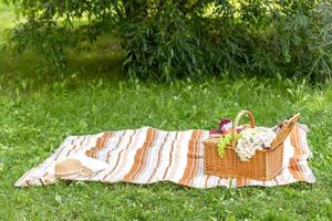 Picnic basket on a plaid and green meadow. Summer picnic concept. Copy space. Banner. photo