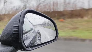 regn droppar rör på sig på en bil sida fönster på hög hastighet i främre av de bak- se spegel. video