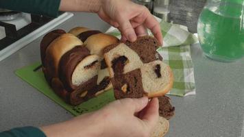 With women's hands, a piece of bread made of white chocolate dough with chocolate inside is cut with a knife. Sweet homemade cakes video