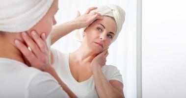 Forty years old woman looking at wrinkles in mirror. Plastic surgery and collagen injections. Makeup. Macro face. Selective focus on the face. photo