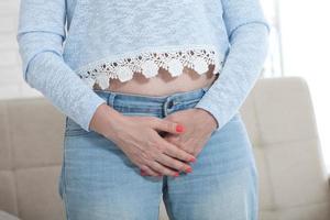 Woman Suffering From Bladder Problem. Woman touching her groin with hands photo