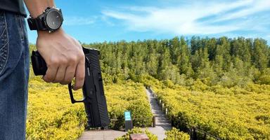 Pistola automática de 9 mm sujeta en la mano derecha del tirador, concepto de seguridad, robo, gángster, guardaespaldas en todo el mundo. enfoque selectivo en pistola. foto