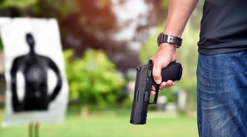 Pistola automática de 9 mm sujeta en la mano derecha del tirador, concepto de seguridad, robo, gángster, guardaespaldas en todo el mundo. enfoque selectivo en pistola.
