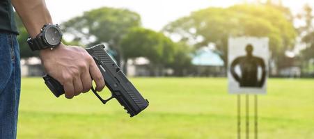 Pistola automática de 9 mm sujeta en la mano derecha del tirador, concepto de seguridad, robo, gángster, guardaespaldas en todo el mundo. enfoque selectivo en pistola. foto