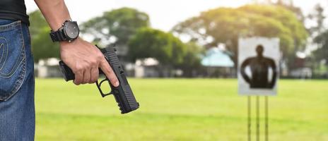 Pistola automática de 9 mm sujeta en la mano derecha del tirador, concepto de seguridad, robo, gángster, guardaespaldas en todo el mundo. enfoque selectivo en pistola. foto