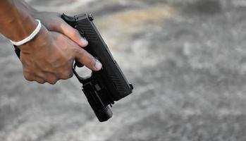 Pistola automática de 9 mm sujeta en la mano derecha del tirador, concepto de seguridad, robo, gángster, guardaespaldas en todo el mundo. enfoque selectivo en pistola. foto