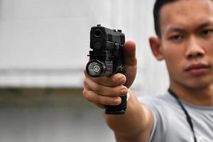 Pistola automática de 9 mm sujeta en la mano derecha del tirador, concepto de seguridad, robo, gángster, guardaespaldas en todo el mundo. enfoque selectivo en pistola. foto