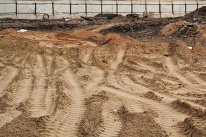 Tire track mark lines shape on dry sand background. Trail tyre imprint from heavy machinery. Vehicle shape. Road construction site backdrop concept. Trace of wheel pattern on mud. Nature texture. photo