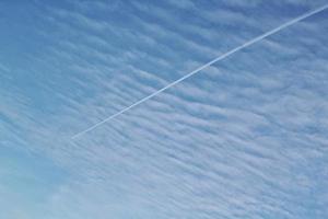 White light soft clouds floating in blue sky and trace of plane. Nature morning landscape background. Clear spring wind. Bright summer day. Winter calm air skyscape. Abstract panorama. Low angle view photo