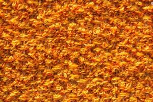 Woven orange wool fabric texture. Hand knitted textile canvas background. Patchwork carpet backdrop. Factory material threads. Abstract design. Close-up, mockup, top view photo