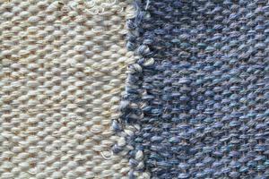 Woven white and blue wool fabric texture. Hand knitted textile canvas background. Patchwork carpet backdrop. Factory material threads. Abstract design. Close-up, mockup, top view photo