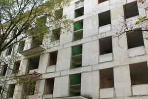 Old evicted and destroyed panel house for demolition with broken windows after resettlement. Recolation and refugee concept. Renovation program. Evacuation from ruined danger damaged building zone. photo