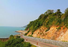 The curve road to the sea and the beach with blue sky and green plant mountain. Beauty of Landscape and Transportation concept photo