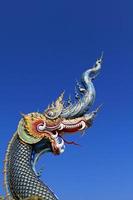 Blue head of Naka or serpent statue opening mouth with clea blue sky background and copy space on above at Wat Rong Sua Ten at Chiang Rai, Thailand. Buddhist Temple and Exterior structure design. photo