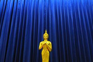 dorado Buda estatua en modelo de azul cortina antecedentes. religión, fe, budista y antiguo, oro objeto con Copiar espacio. foto