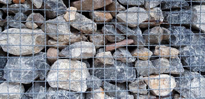 Many rock, stone or limestone in steel netting or net barrier for background. Group of object, Wallpaper and Hard material photo