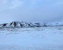 Icelandic winter landscape with snow covered hills and blue cloudy sky photo