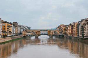 Front symmetrical view old town medieval bridge over gloomy waters and colorful buildings photo