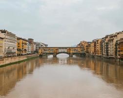 Front symmetrical view old town medieval bridge over gloomy waters and colorful buildings photo