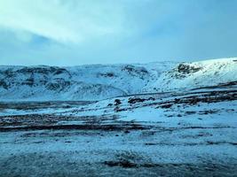 Icelandic winter landscape with snow covered hills and blue cloudy sky photo