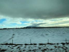 Icelandic winter landscape with snow covered hills and blue cloudy sky photo