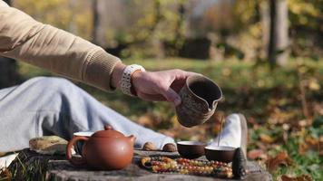 from a clay pot a man pours tea