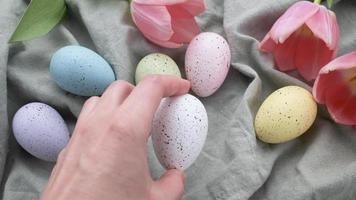 un mujer mano pone un de colores Pascua de Resurrección huevo en el mesa. video