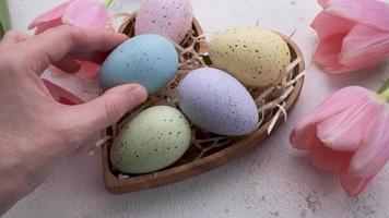 A woman's hand puts a colored Easter egg on the table. video