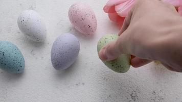 A woman's hand puts a colored Easter egg on the table. video