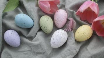 Pink decorative feathers fall on a table with colored Easter eggs. video