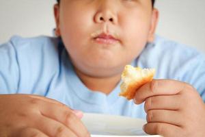 el grasa chico también mucho peso comer Pizza con un lote de masa foto