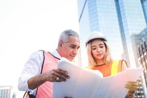 civil ingenieros y joven arquitectos, multiétnico edificio diseñadores trabajando juntos en un Plano, encuesta planificación equipo reunión. urbano desarrollo conceptos, modernización de público utilidad sistemas foto