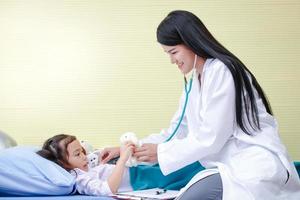Asian female doctors use stethoscope to check the heartbeat A little girl in a hospital bed. Concept of child care.